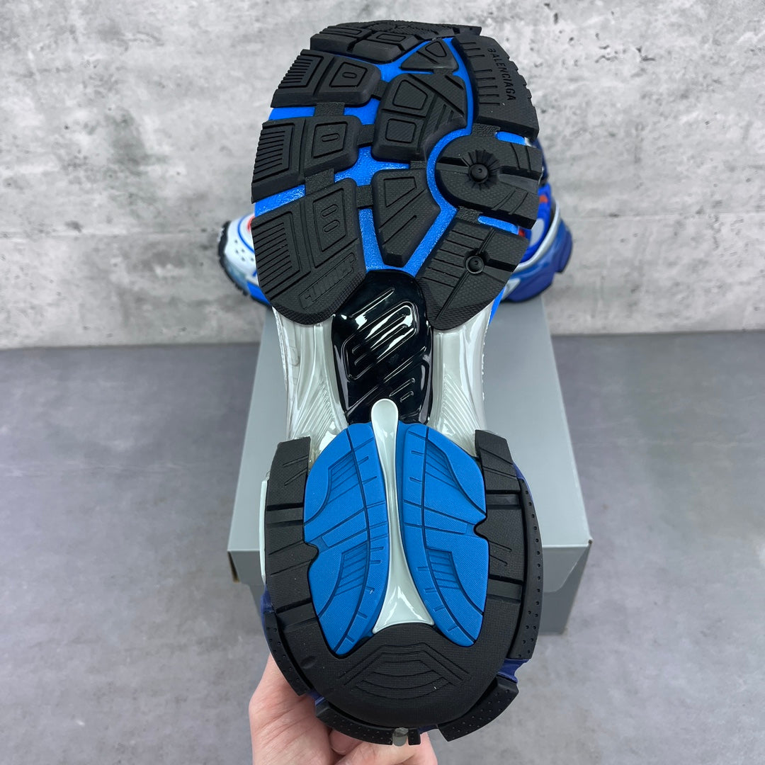 Outsoles of blue and black chunky sneakers with tread patterns and white midsole.