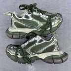 Chunky sneakers with green laces, white and silver panels, and textured mesh uppers