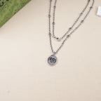 Double-row silver chain necklace with oval logo pendant
