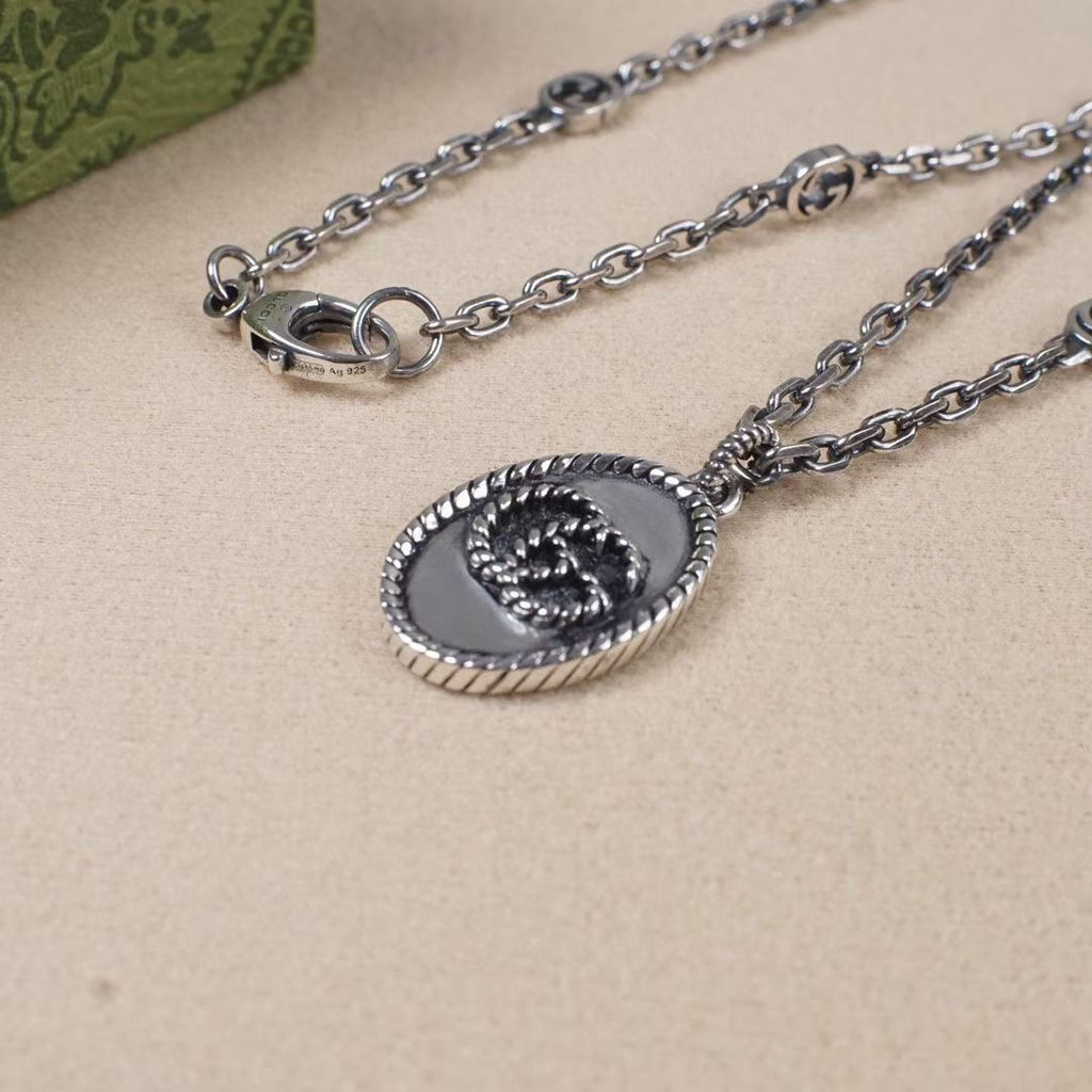 Silver chain necklace with oval logo pendant close-up