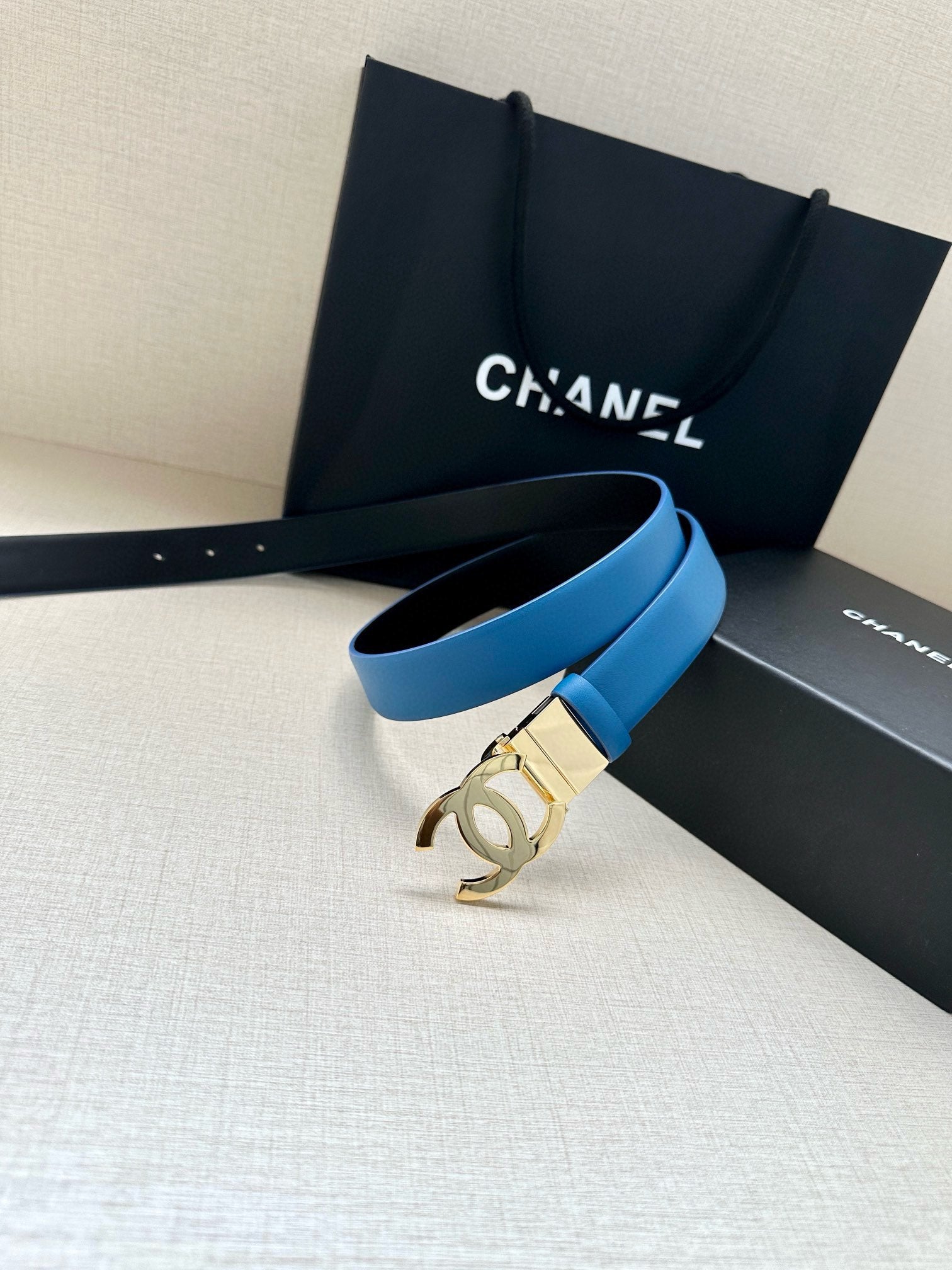 Blue leather belt with gold-tone buckle and black pouch on display