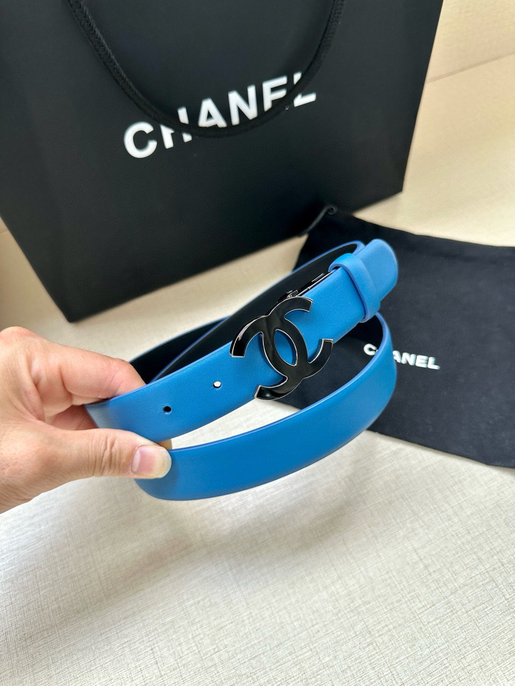 Blue leather belt with silver CC buckle and visible strap holes