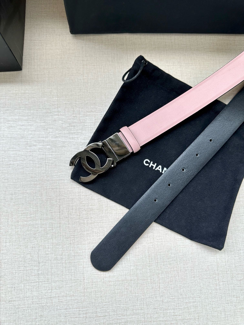 Chanel belt with pale pink strap and silver CC logo buckle on dark underside
