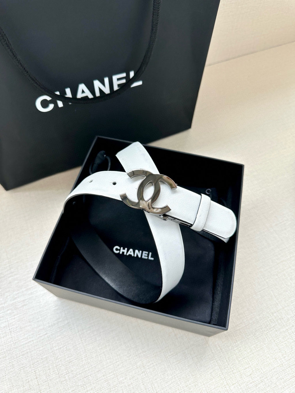 White leather Chanel belt with silver CC buckle and adjustable strap in box
