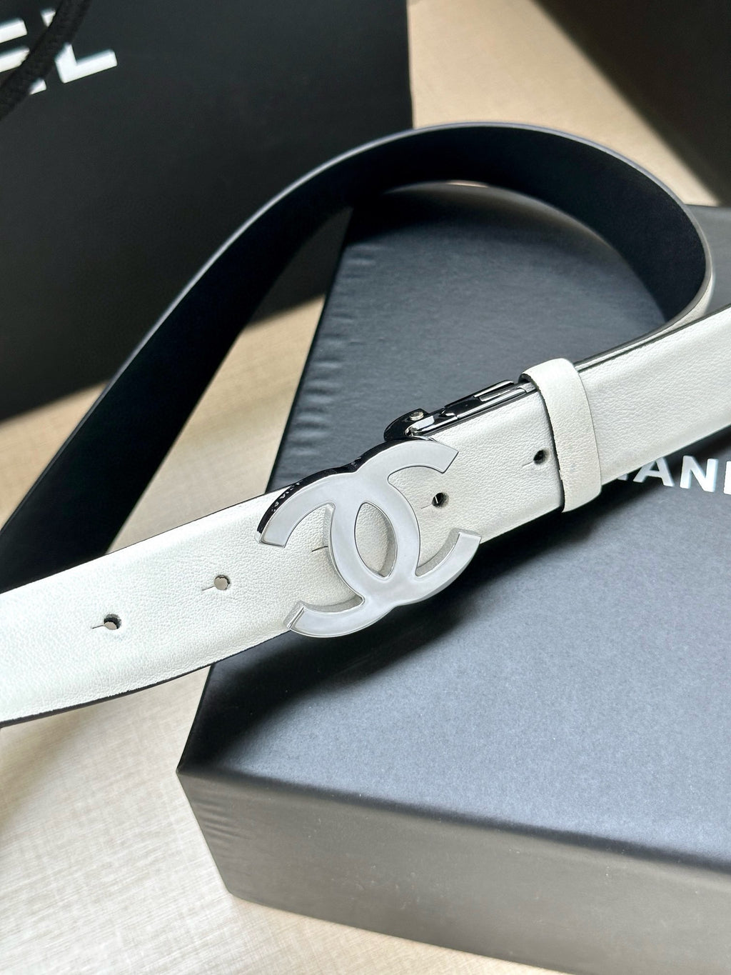 White leather Chanel belt with silver buckle and embossed logo detail