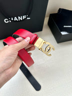 Red leather Chanel belt held in hand with gold-tone CC buckle.