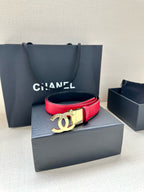 Red leather Chanel belt resting on a box with a gold-tone CC buckle.