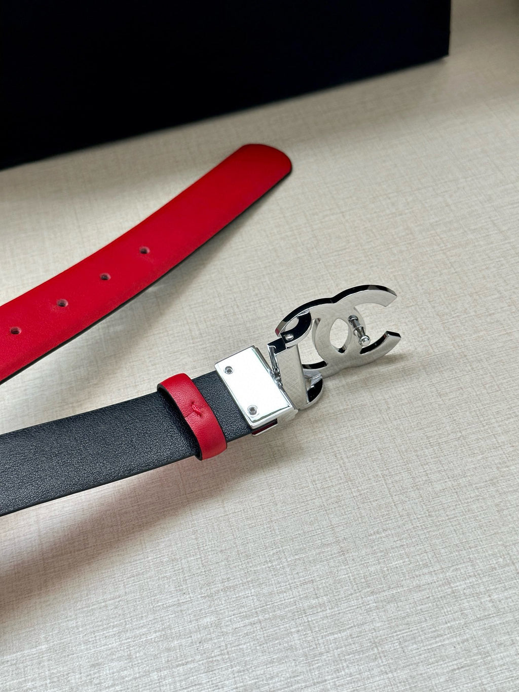 Red leather belt with silver-tone buckle, showing the metal clasp detail.