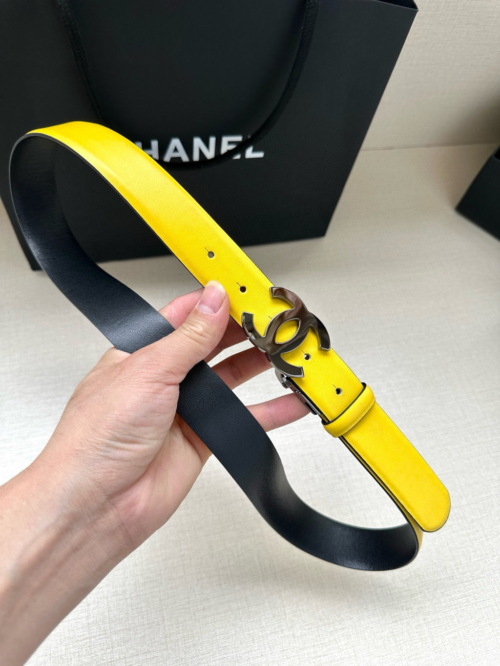 Yellow leather belt with metal Chanel logo buckle, side view
