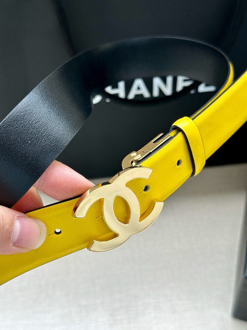 Yellow leather belt close-up with large metal Chanel logo buckle