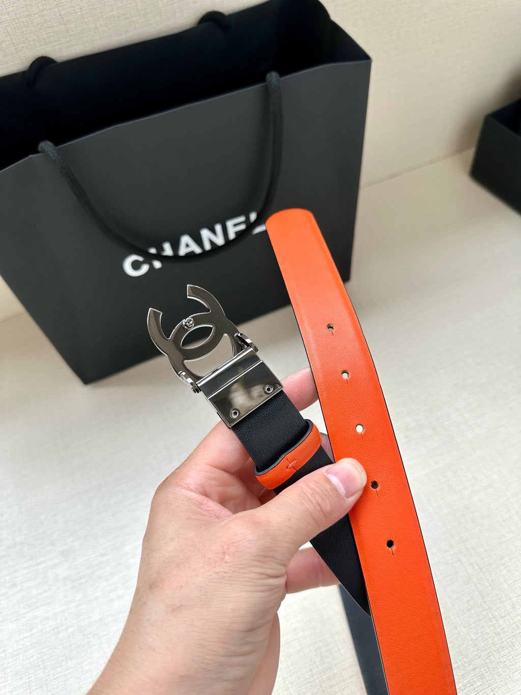 Chanel orange-and-black belt with silver buckle and CC-style hardware