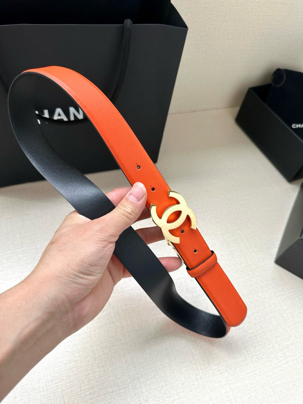 Chanel orange leather belt with black underside and CC logo buckle