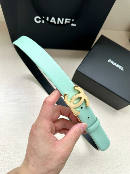Chanel belt in light mint leather with gold CC buckle, held up by hand.