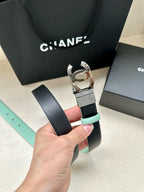 Chanel belt with black leather strap and silver CC buckle, held up by hand.