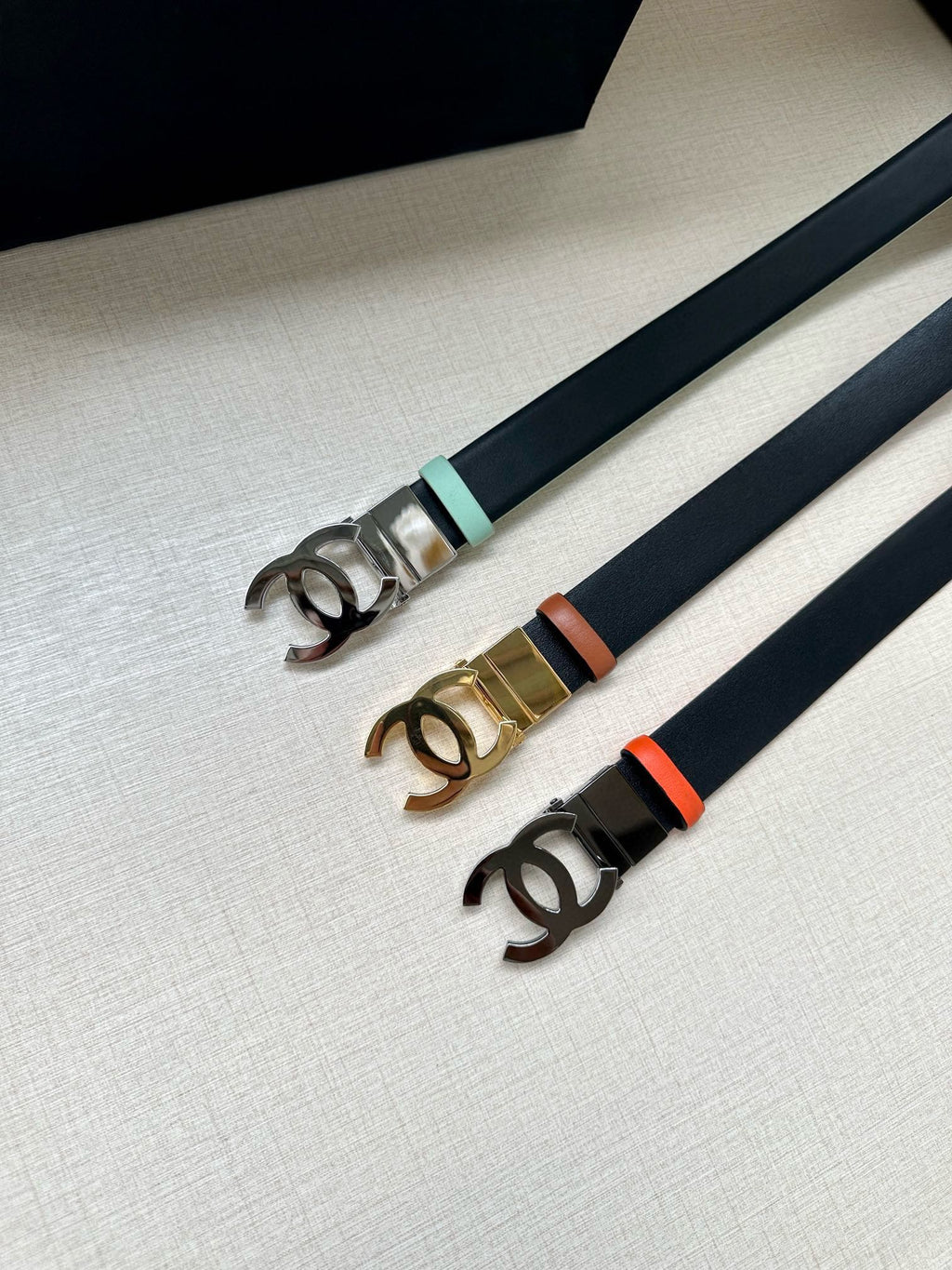 Chanel belt set with dark straps and CC buckles in silver, gold, and mint tones.