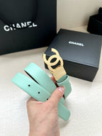 Chanel belt in light mint leather with gold CC buckle, held in hand.