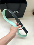 Chanel belt with black strap and light mint leather trim, held up by hand.