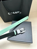 Chanel belt with mint edge and black strap, silver CC buckle on gray box.