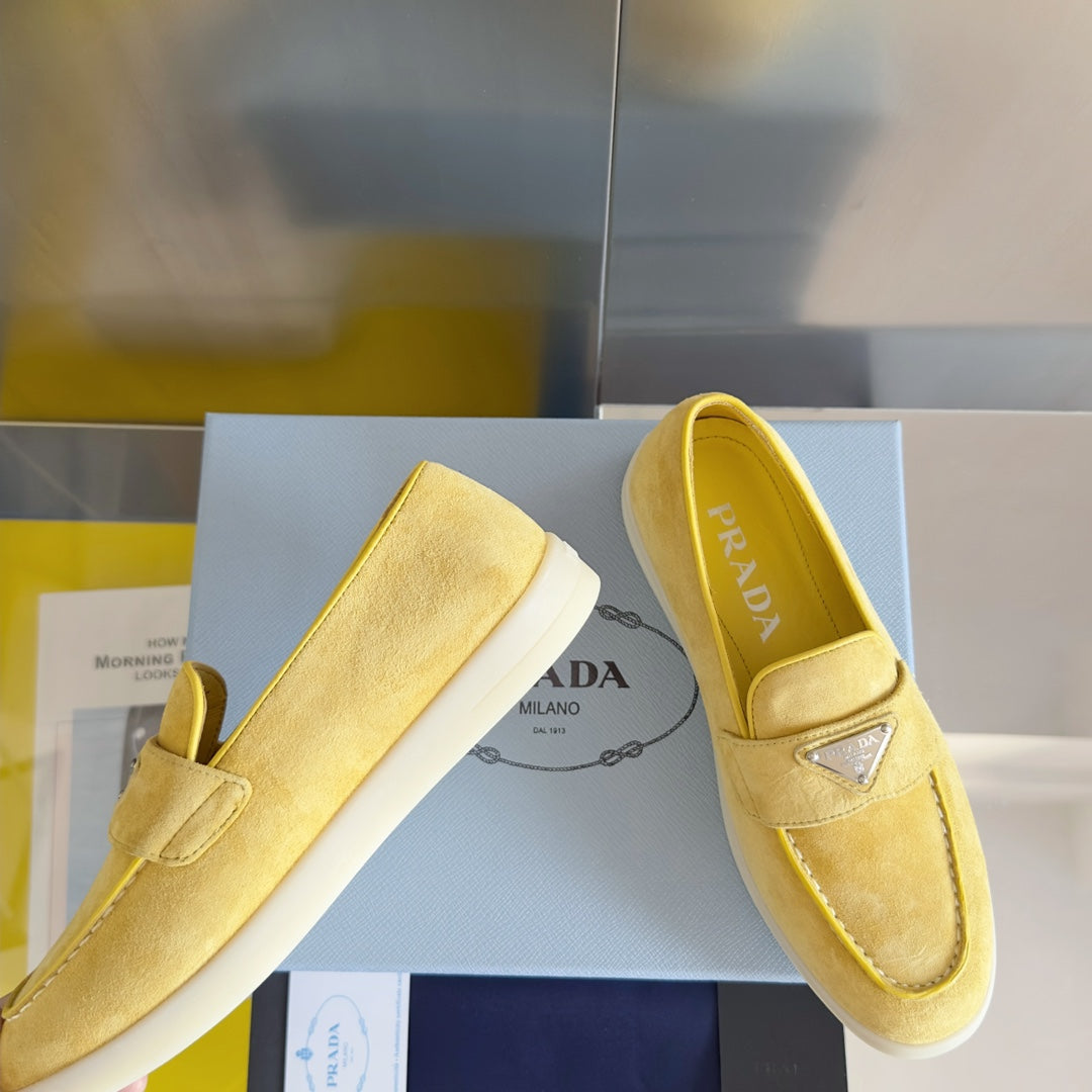 Prada suede loafers, bright yellow/gold, shown from front with strap and logo badge