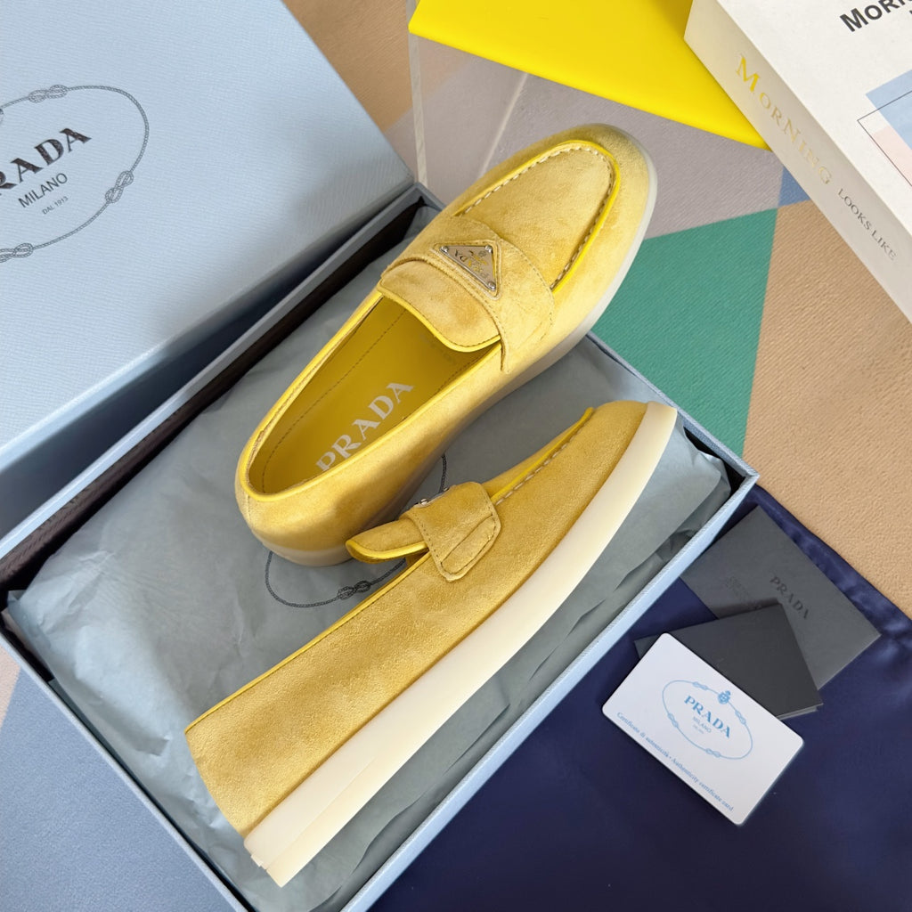 Prada suede loafers in bright yellow/gold, side view with slip-on upper and logo detail