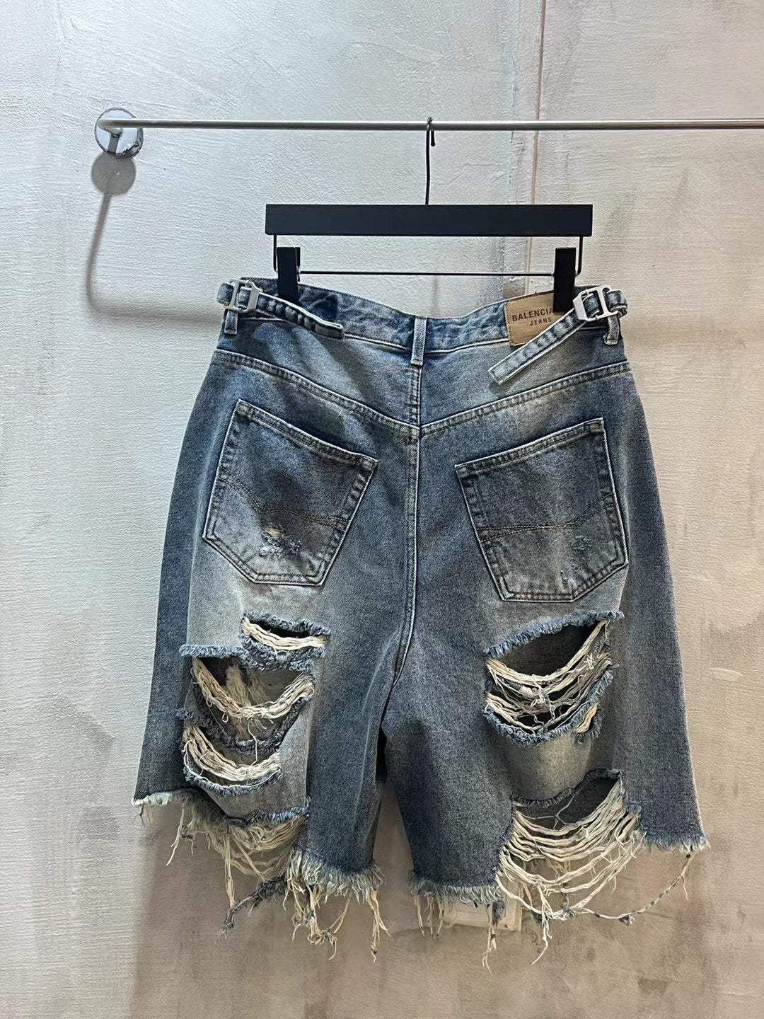 Balenciaga denim shorts with multiple ripped details, frayed hem, light blue wash