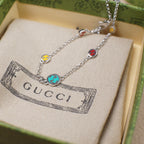 Gucci charm bracelet displayed on fabric pouch, silver chain with enamel charms