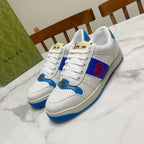 White and blue lace-up low-top sneakers with red logo patch and perforated toe