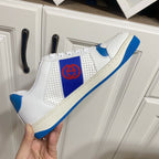 White and blue lace-up low-top sneakers with red logo patch and blue outsole edge