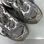 Close-up of lace-up sneakers with gray mesh, silver accents, and a thick sole