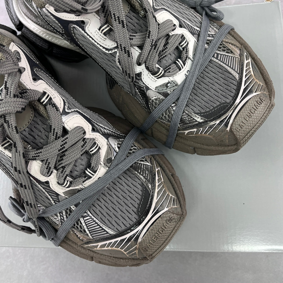 Close-up of lace-up sneakers with gray mesh, silver accents, and a thick sole