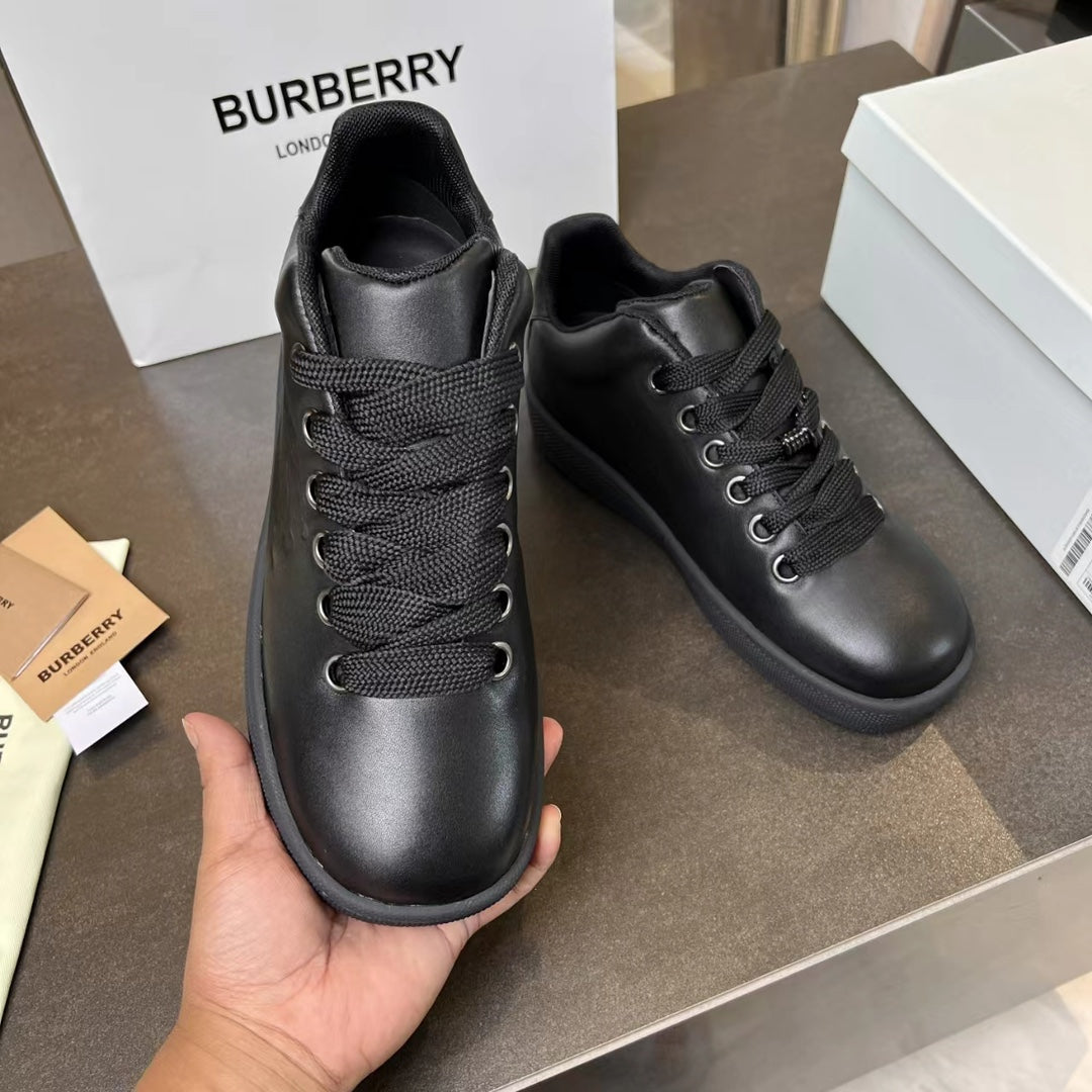 Black lace-up sneakers held in hand with cushioned collar and rubber outsole