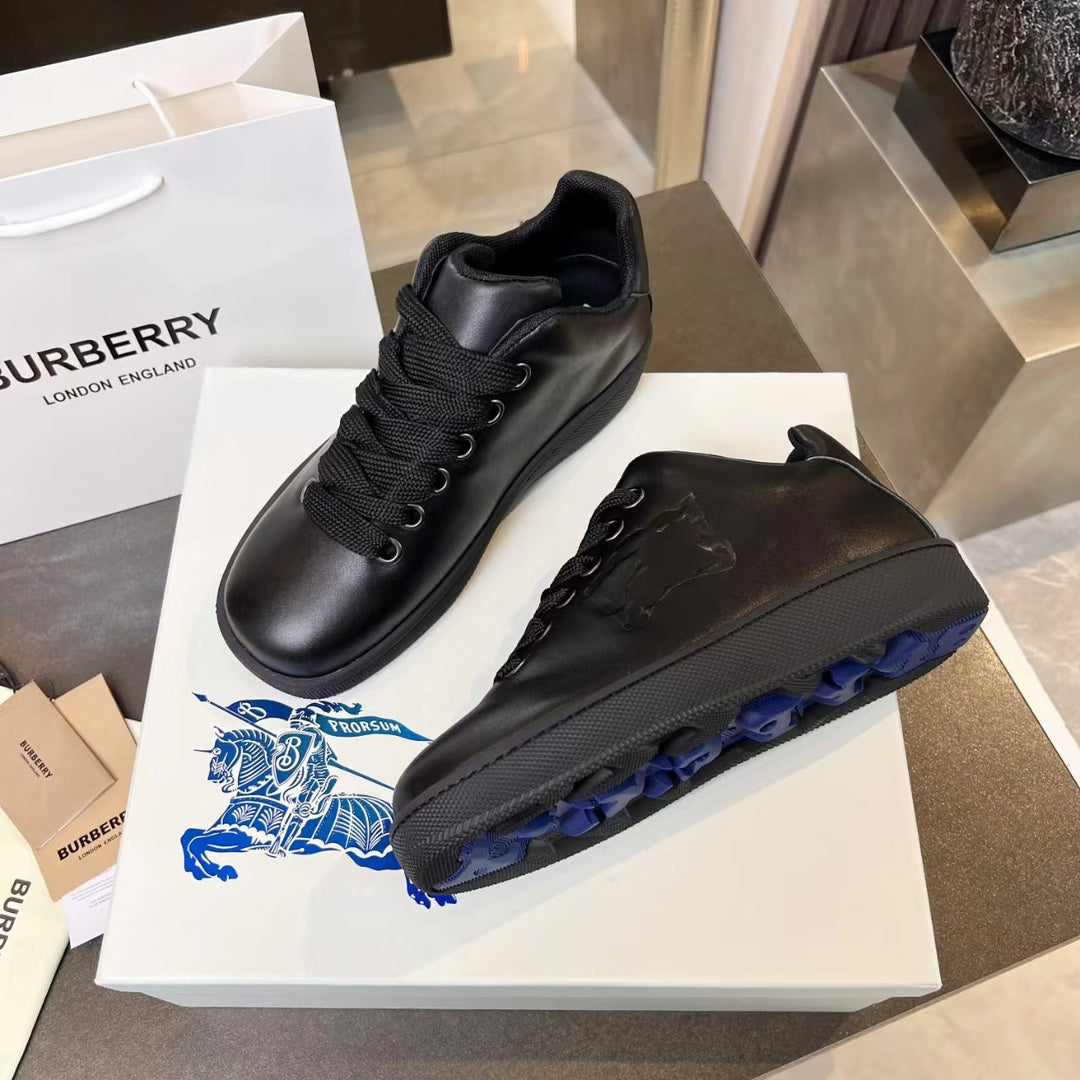Black lace-up sneakers with embossed pattern and blue-accent outsole tread