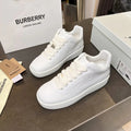 Pair of white low-top lace-up sneakers with textured panels and gold-tone eyelets