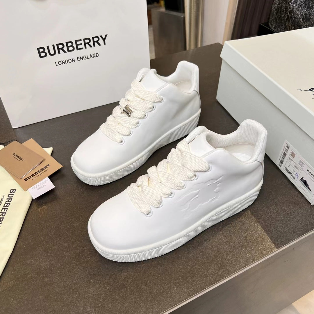 Pair of white low-top lace-up sneakers with textured panels and gold-tone eyelets