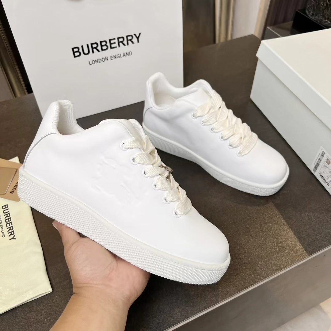 White low-top sneakers with lace-up front, textured upper, and thick white sole