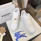 Pair of white lace-up sneakers on box, with textured logo hardware