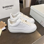White low-top lace-up sneakers with embossed pattern and gold-tone eyelet detail