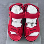 Pair of red Balenciaga sandals on box with two adjustable hook-loop straps