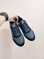 Navy leather sneakers being held; lace-up design with white rubber sole
