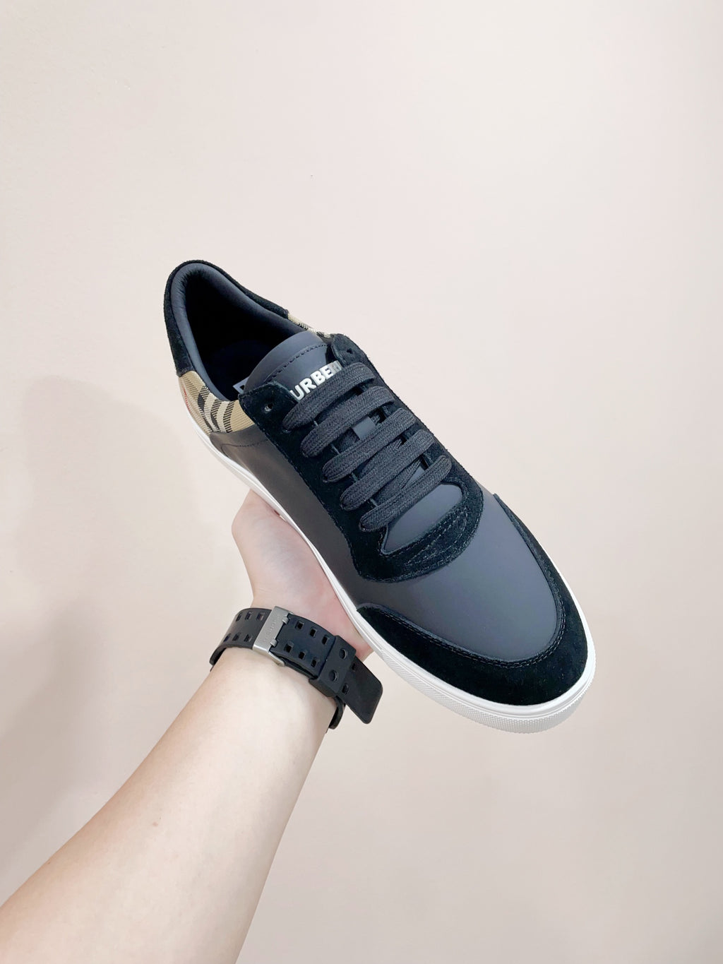 Navy leather sneakers on wrist; lace-up style with white rubber sole