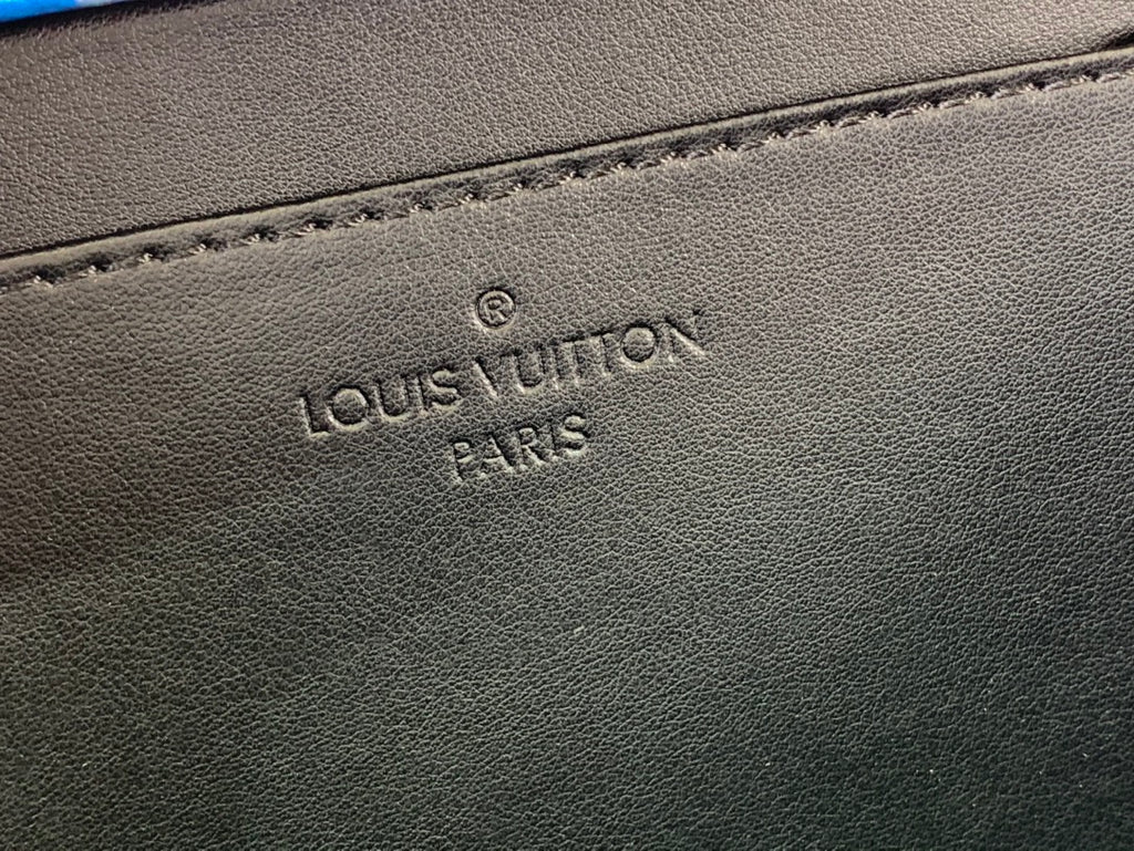 Embossed “Louis Vuitton Paris” on dark leather bag exterior close-up