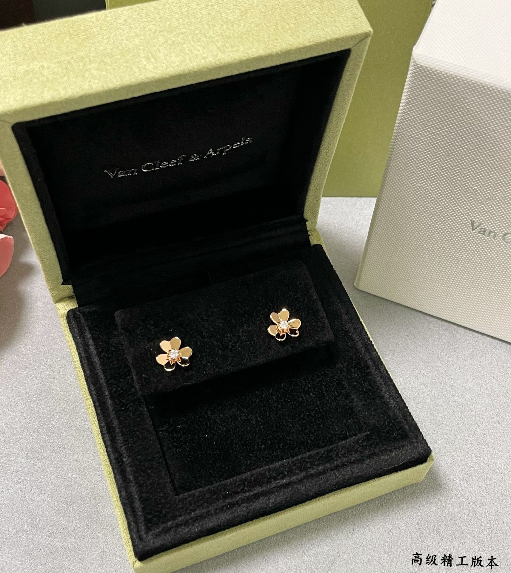 Gold clover stud earrings in a black velvet display box