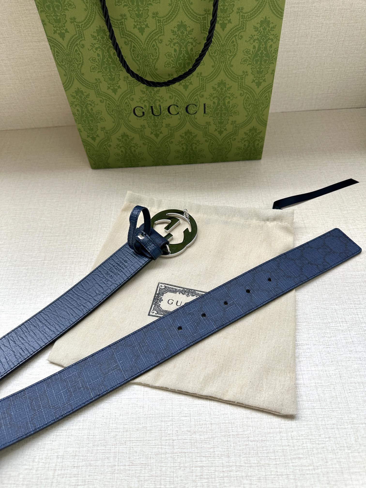 Gucci belt on white pouch with dark blue strap and small silver interlocking G buckle