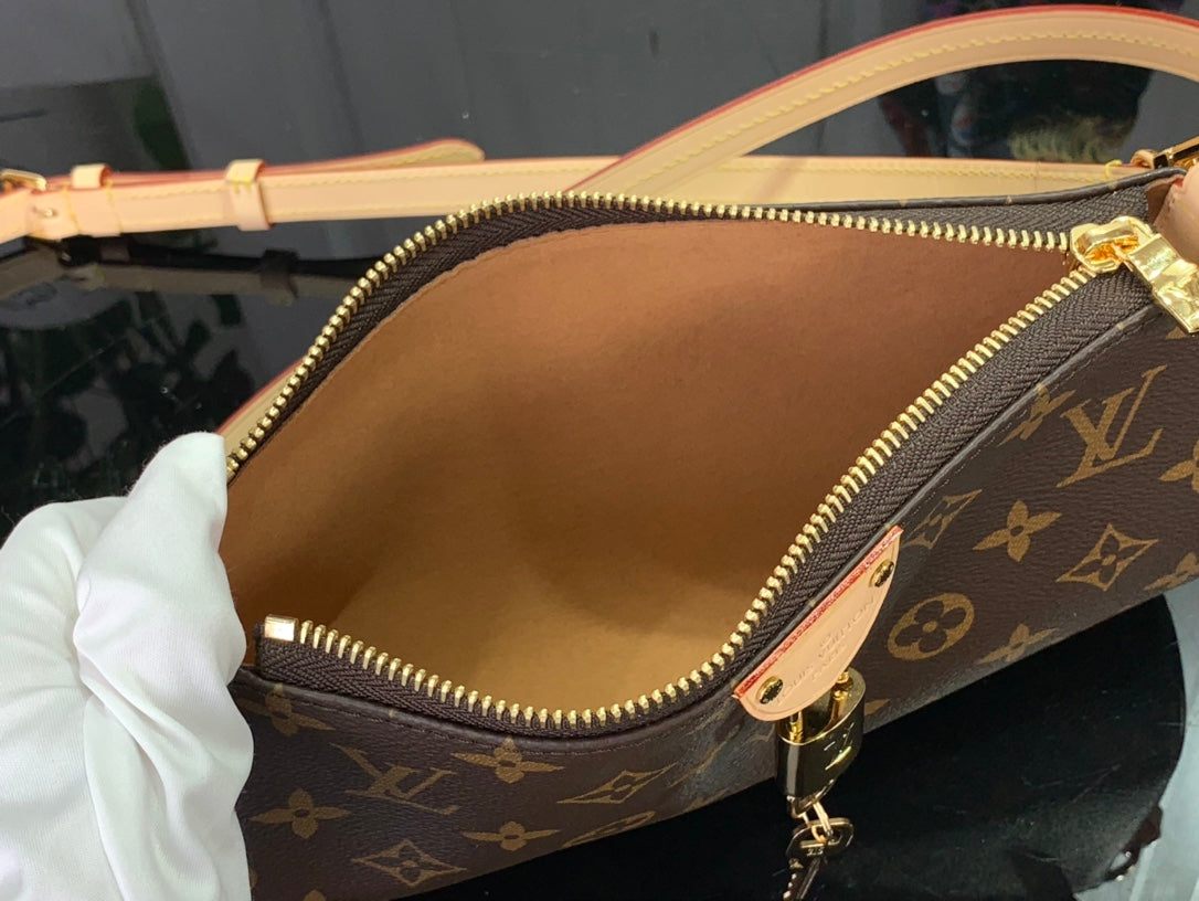 Louis Vuitton monogram bag open with tan lining and gold zipper pulls, close-up