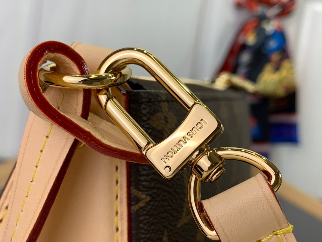 Louis Vuitton monogram bag clasp with tan strap and gold hardware, close-up