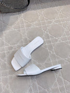 White Balenciaga slide sandals with metal-look heel detail and embossed logo strap