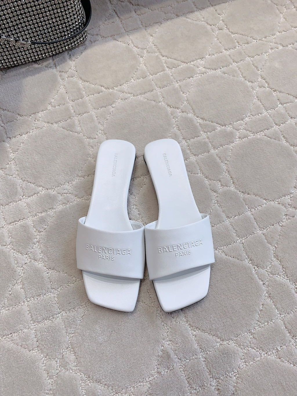 White Balenciaga slide sandals with single wide strap and embossed logos