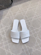 White Balenciaga slide sandals with single wide strap and embossed logos