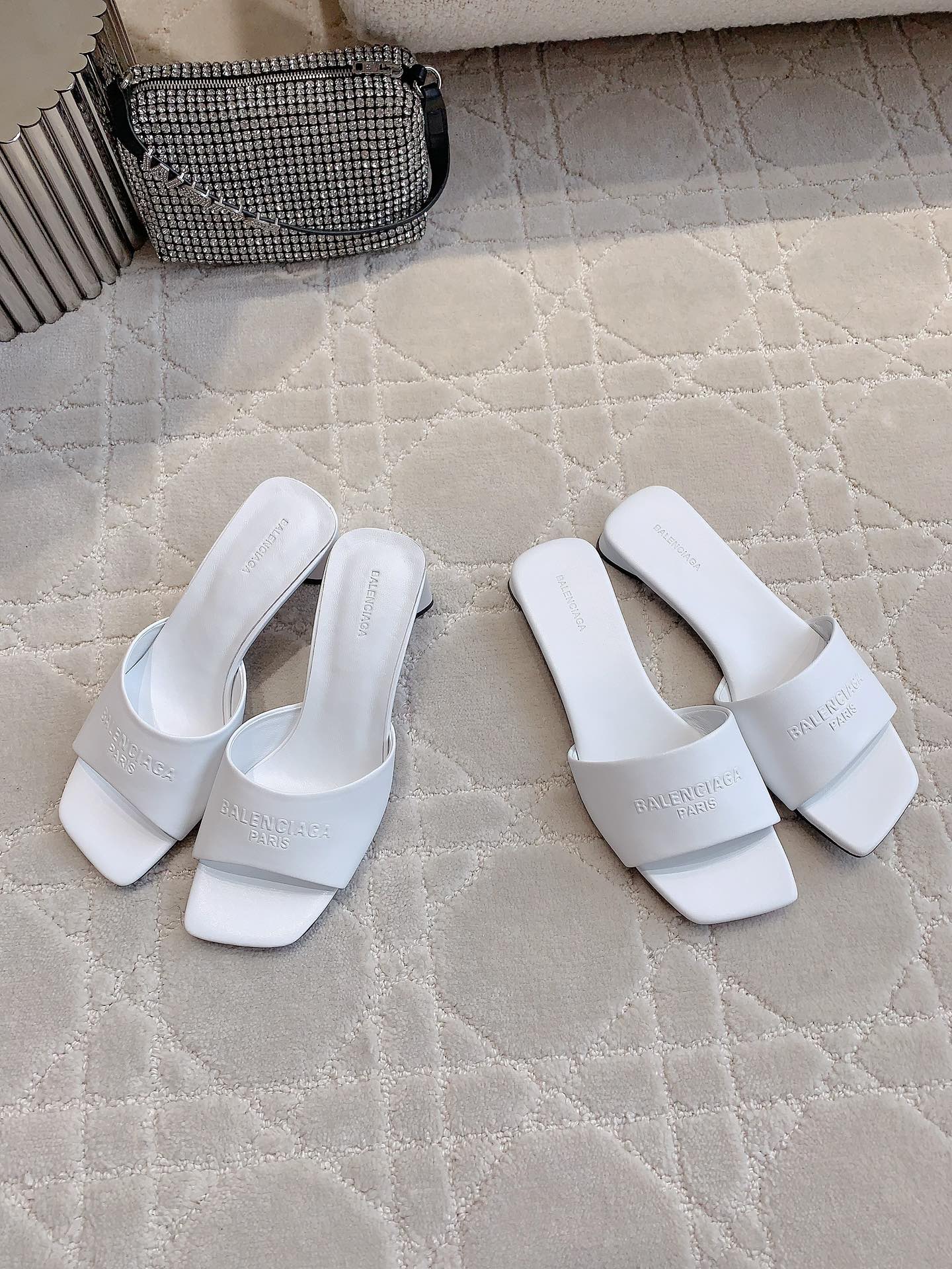 White Balenciaga slide sandals with wide straps and embossed branding on footbed