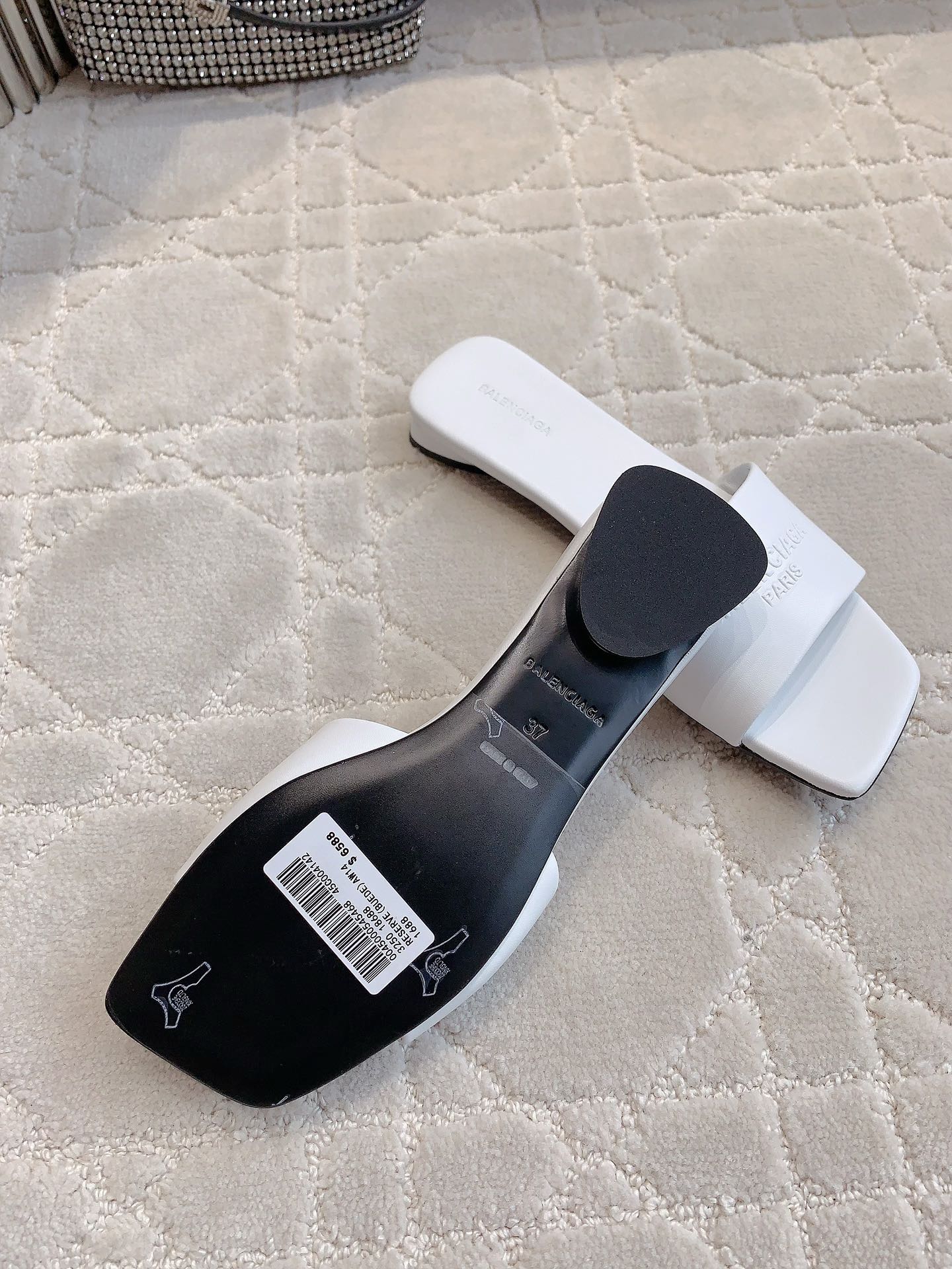 White slide sandals with black heel insert and barcode label on underside